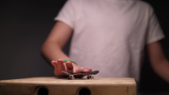 KID DOING FINGER SKATEBOARD TRICK, IN SLOW MOTION