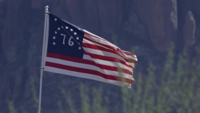 American 76 flag wide shot against mountains slow motion