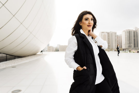 stylish young woman in a black suit posing against the background of the unusual architecture of the city of Baku, smiling