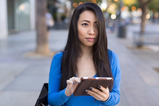 Young Asian woman walking using tablet computer