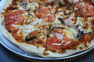 Seafood pizza , with mussel squid shrimp and tomato , italian food