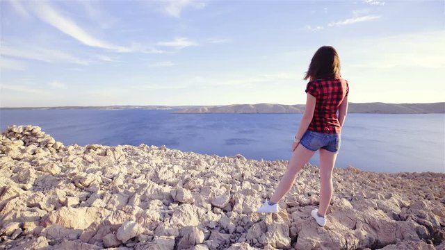 Woman looking at sea from top of stones 4K