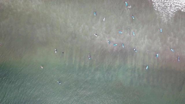 An aerial view of surfers waiting for a wave in the ocean on a clear day. Aerial view of surfer on huge Indian ocean wave. Surfers on the beach top view