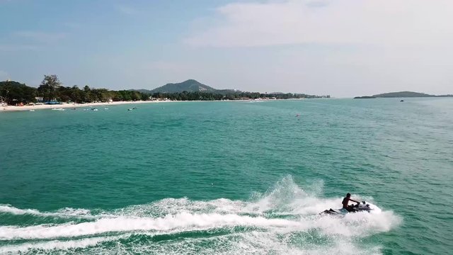 Man riding on a jet ski. Aerial view man driving a jet-ski at sea. Jet ski on the water of the sea. Man riding a water bike jetski. Travel concept. People are playing a jet ski in the sea. Top view.