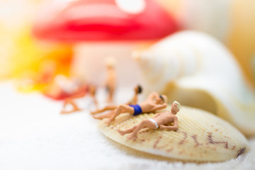 Miniature people : Group travelers sunbathing on shells at the beach . Image use for business travel concept.
