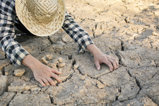 Asian man on cracked dry ground, concept drought and crisis environment