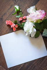 Artificial flowers on wood background with white paper for copy space 