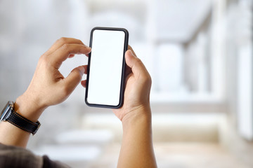 Mockup image of man hands holding black mobile phone with blank white screen in office