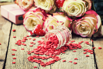 Red sweet heart, Valentines Day card on background of fresh pink and white roses, selective focus