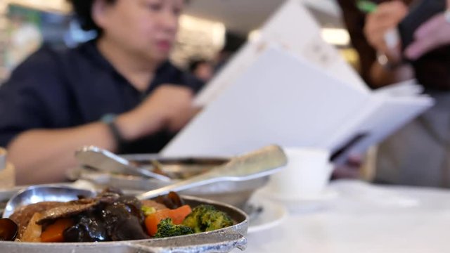 Blur Motion Of Waitress Taking Order For Customer Inside Chinese Restaurant, Focus Of People Eating Meatball