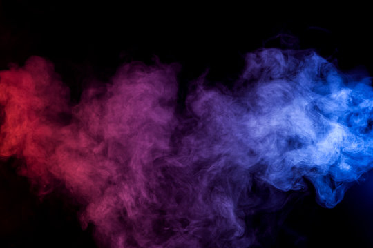 Dense multicolored smoke of   red and blue colors on a black isolated background. Background of smoke vape