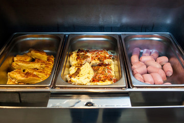 Close-up metal bowls for self-catering with an omelette made from sausage with tomatoes, sausages, pastries. Breakfast at the hotel