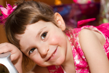 Close-up Portrait of a pretty smiling little Toddler girl in beautiful pink dress with brown hair and pink flower hair clip 