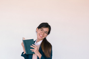 Young Asian businesswoman wearing blue suit and holding a book  and reading