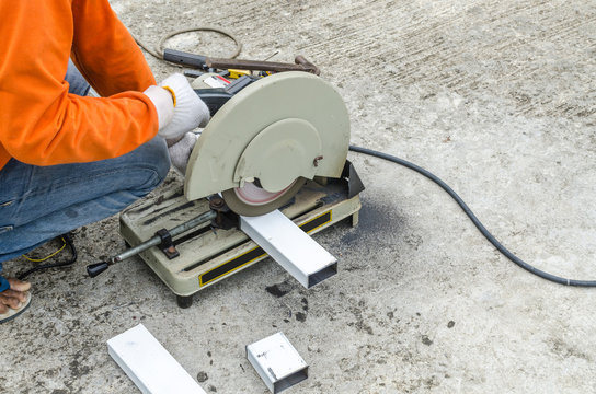 asian worker with machine cutting metal and welded steel to create a roof, local labor construction concept