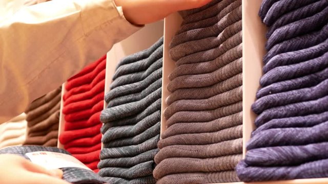 Motion of shopper buying socks at display socks cabinet inside uniqlo store with 4k resolution