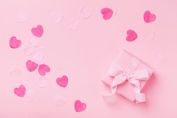 Gift or present box and paper hearts on pink table top view. Greeting card for Valentines, Woman or Mothers Day. Flat lay.