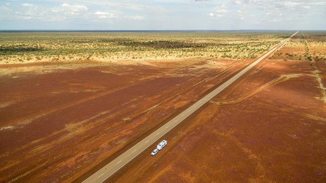Aerial view of caravan and four wheel drive parked alongside a straight highway in the outback of Australia