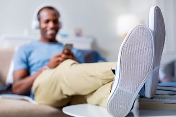 Fototapeta premium Comfortable position. Selective focus of feet being put on the table by a cheerful nice relaxed man while resting at home