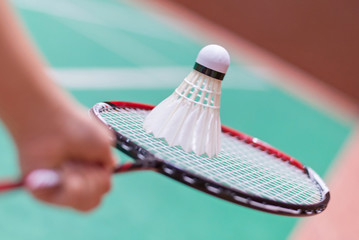 kid holding badminton racket and shuttlecock  in badminton court