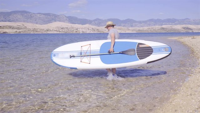 Person carry sup board in to water 4K