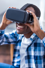 Technological progress. Joyful positive young man smiling and holding 3d glasses while using virtual technologies