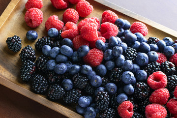 Assorted variety of fresh fruit on wooden tray