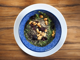 grüner Smoothie mit Avocado in blauer Schüssel auf Holztisch