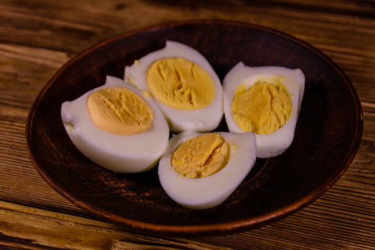 Ceramic plate with peeled boiled eggs on wooden table