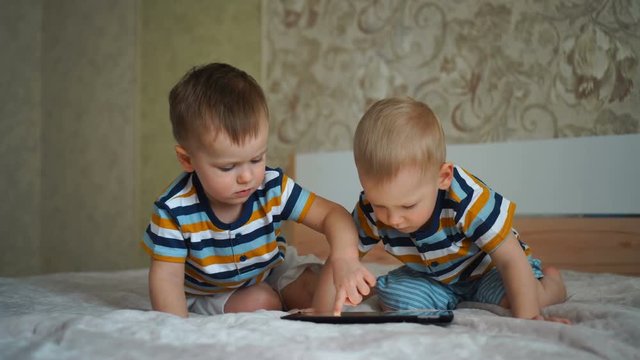 Two little boys are playing on a tablet computer.