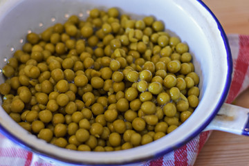 Boiled peas in white pot at wooden background/ closeup still life food photography