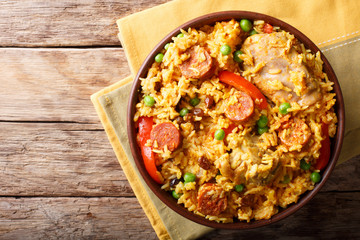 Arroz Valenciana with rice, meat, sausage, raisins, vegetables and spices close up in a bowl. horizontal top view