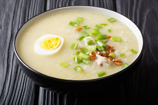 Hot Arroz Caldo traditional rice soup with chicken, vegetables and egg close-up in a bowl. horizontal
