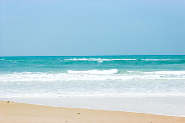 waves with foam of blue ocean on the sandy beach
