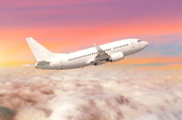 Fototapeta na wymiar Flying airplane above the clouds horizon sky with bright sunset colors.