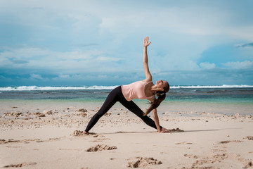 Fototapeta na wymiar Yoga woman. Extended triangle pose asana. Ocean background