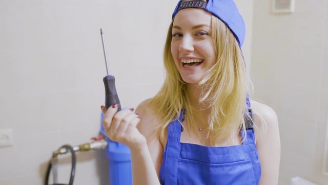 Pretty girl in overalls put her screwdriver into a pocket