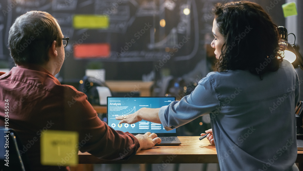 Poster male and female financiers look at statistics and graphs shown on the laptop, they talk solving prob