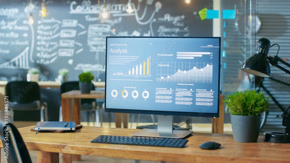 Poster Personal Computer with Mobile Application Design Showing on the Monitor Stands on the Office Desk, In the Background Man Working in the Daytime Office Environment.