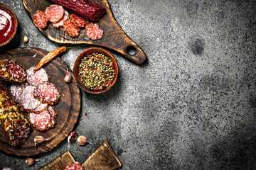 Obraz na płótnie Canvas Different kinds of salami with spices and herbs on old boards.