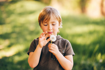 Fototapeta premium Adorable kid boy playing with dandelion in spring park