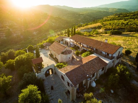 Aerial bird's eye view of Holy monastery of Archangel Michael (Archangelou Michail) in Monagri village, Limassol, Cyprus, an ancient christian religious monument, at sunset flare, from above.