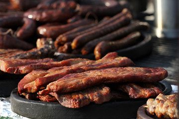 Variety of different kind of meat steaks, meatballs, shish kebab, fillet, burgers and sausages with bread on a grill outdoor. Grilled meat on a barbecue