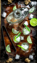 Vodka with lime and ice on a wooden tray.