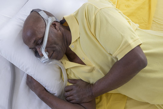 Healthcare concept,African, American Man with obstructive sleep apnea sleeping well with cpap machine ,Man laying in bed wearing cpap mask, on white backgroud