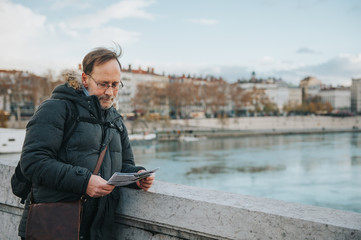 Man tourist with backpack and map admiring Rhone river from Bonaparte Bridge, Lyon, France.