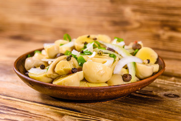 Ceramic plate with canned mushrooms on wooden table