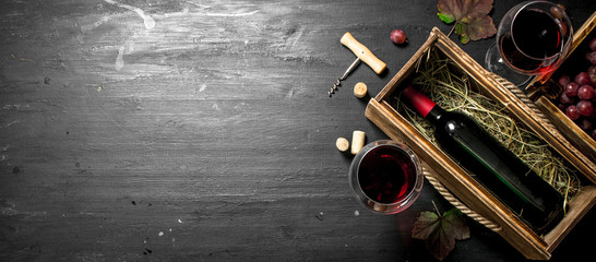 Wine background. Red wine in an old box with a corkscrew.