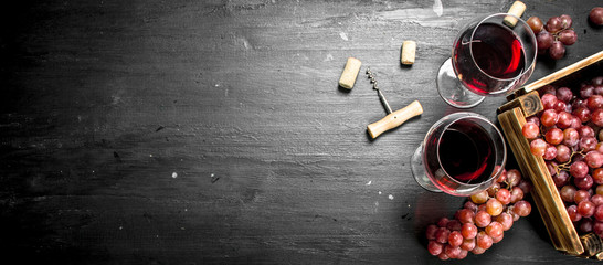 Wine background. Red wine in an old box with a corkscrew. - obrazy, fototapety, plakaty