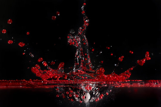 Red polystyrene  spherules splashing in water